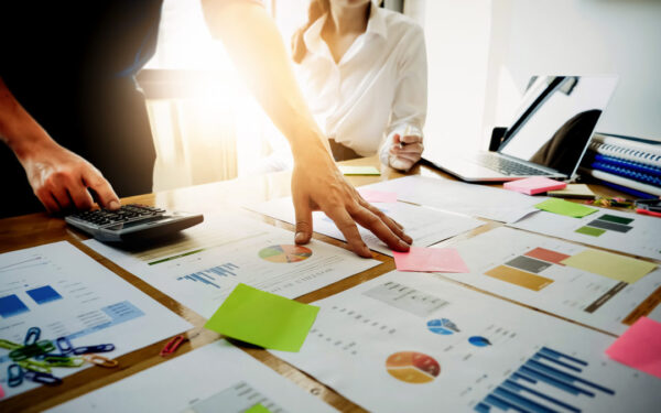 Businessman calculator and business woman holding pen are meeting to plan sales to meet targets set in next year.